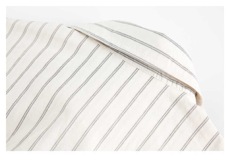 Close-up of the pointed collar and striped fabric of an off-white shirt.