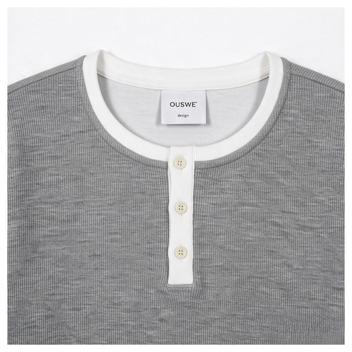 Close-up of a gray ribbed top's front with a white crew neck and three-button placket.