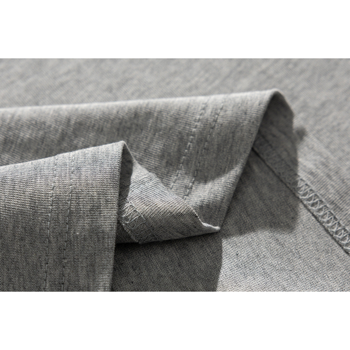 Close-up of gray garment fabric showing a folded hem and visible stitching.