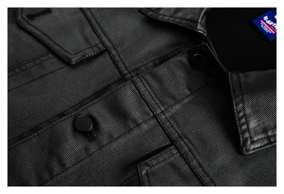 Close-up of a black jacket front showing stitched panels, flap pockets, and black snaps.