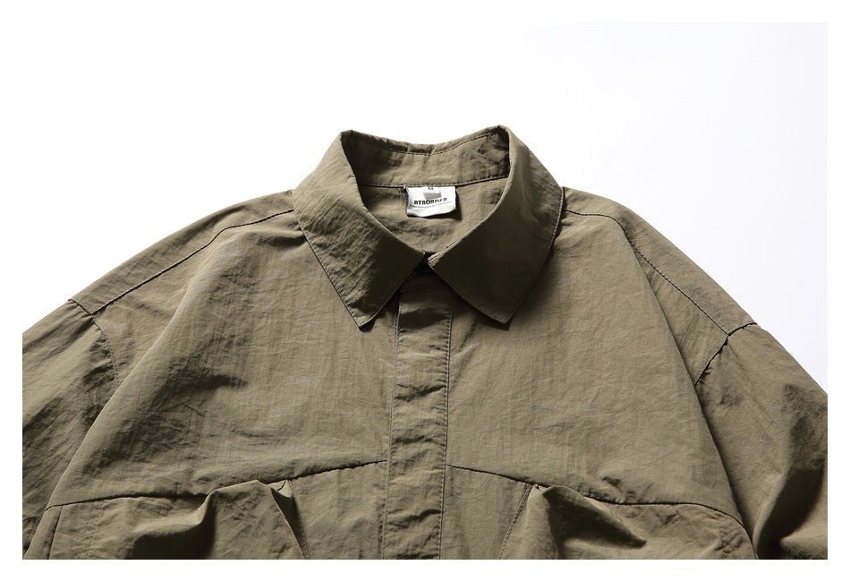 Close-up of the olive-brown shirt's pointed collar, front placket, shoulder seams, and sewn neck label.
