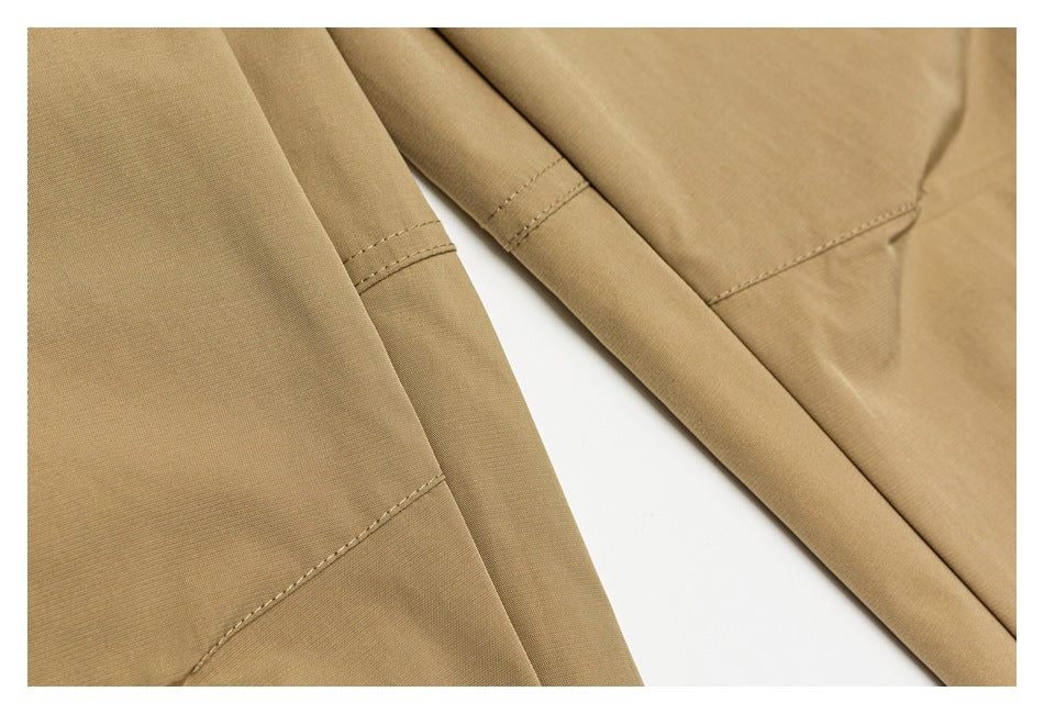 Close-up of tan pants showing overlapping leg panels and stitched seams.