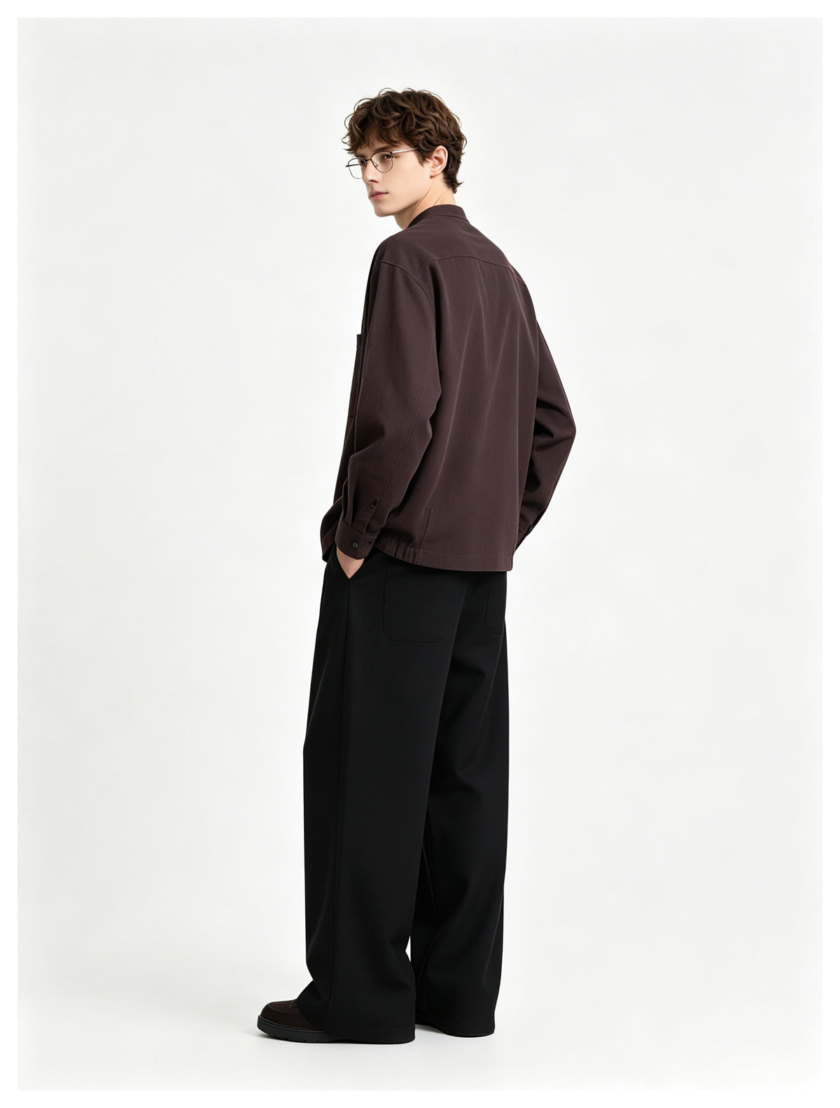 Model turned to show the back of a dark brown long-sleeved shirt with a back yoke and buttoned cuffs.