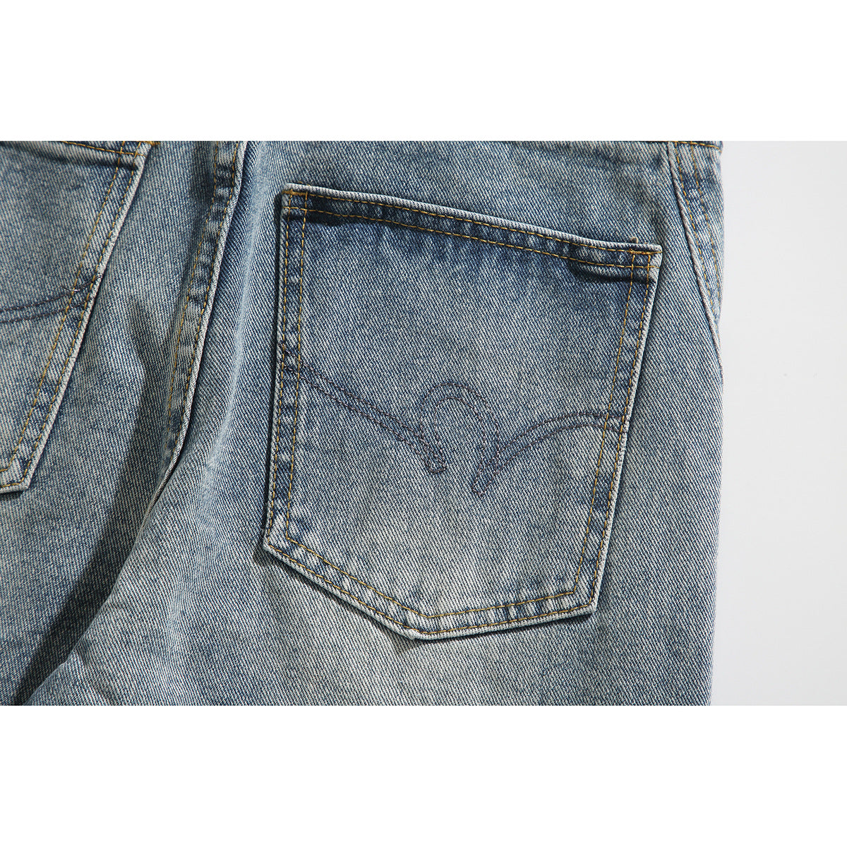 Close-up of a back pocket on light-wash jeans, with curved decorative stitching.