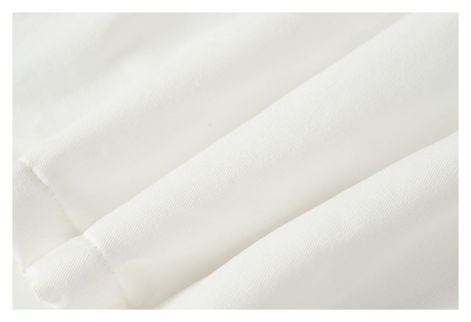 Close-up of white garment fabric with diagonal folds and a visible seam.