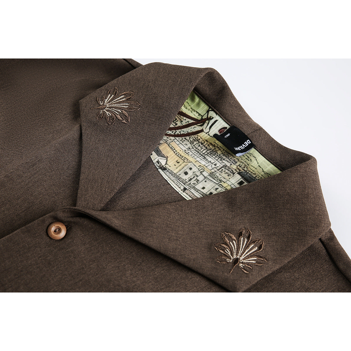 Close-up of a brown collared garment with embroidered floral motifs, a button, and illustrated lining.