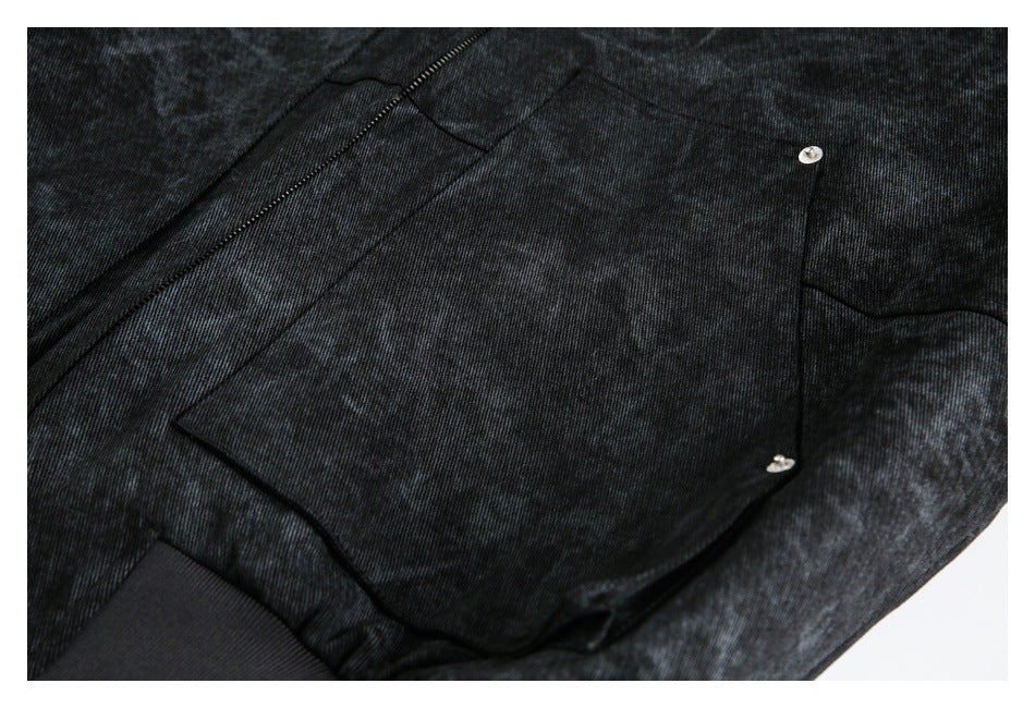 Close-up of a dark charcoal jacket pocket flap with two silver snaps and nearby zipper stitching.