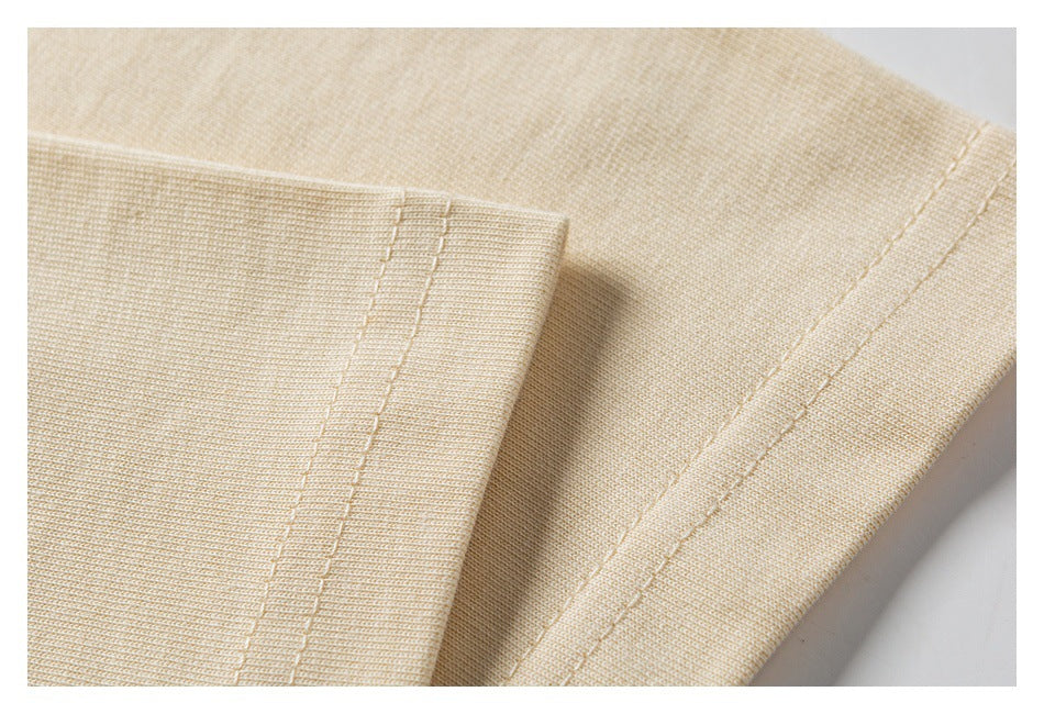 Close-up of light beige knit garment fabric with a folded edge and parallel rows of stitching.