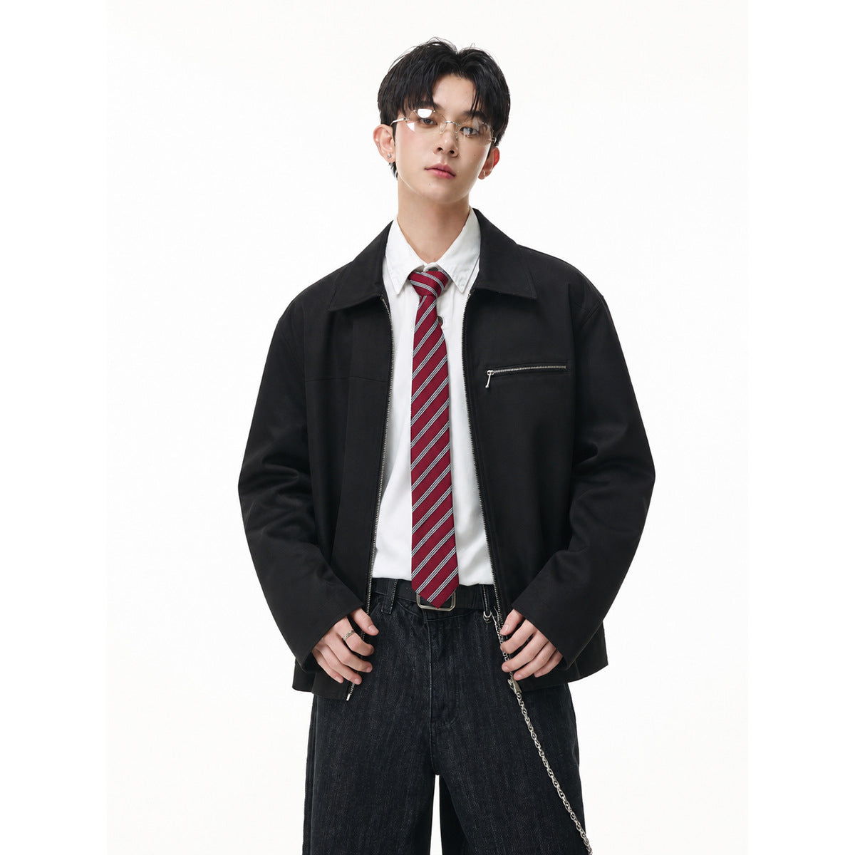 Model wearing a black zip-front jacket with a pointed collar and horizontal chest zipper pocket.