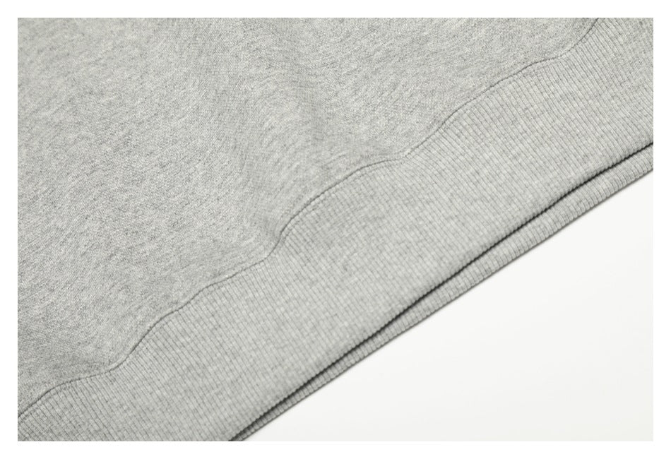 Close-up of the gray sweatshirt fabric and wide ribbed hem along a diagonal edge.