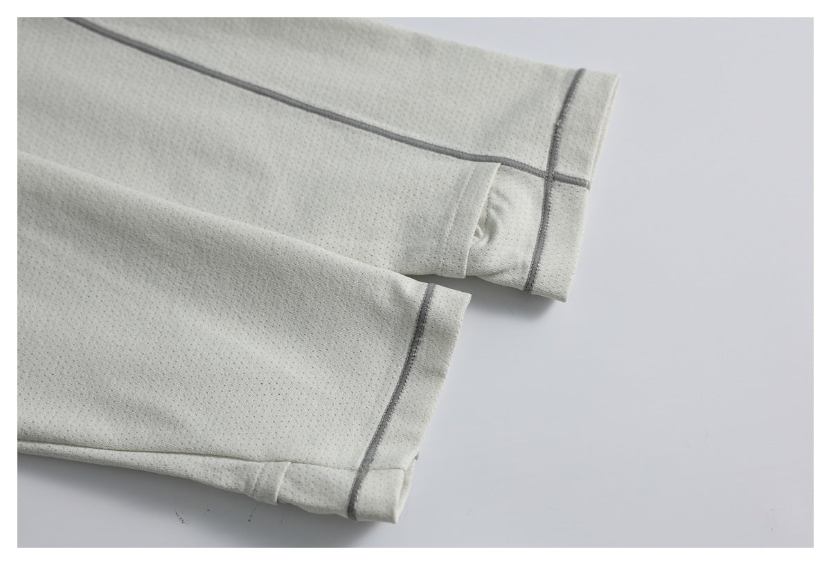 Close-up of two light beige garment cuffs with perforated fabric and dark gray piping.