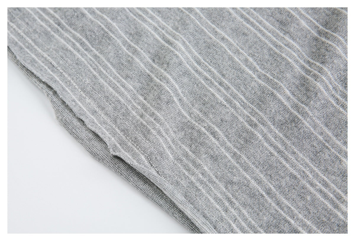Close-up of the edge seam on gray knit fabric with thin white stripes.