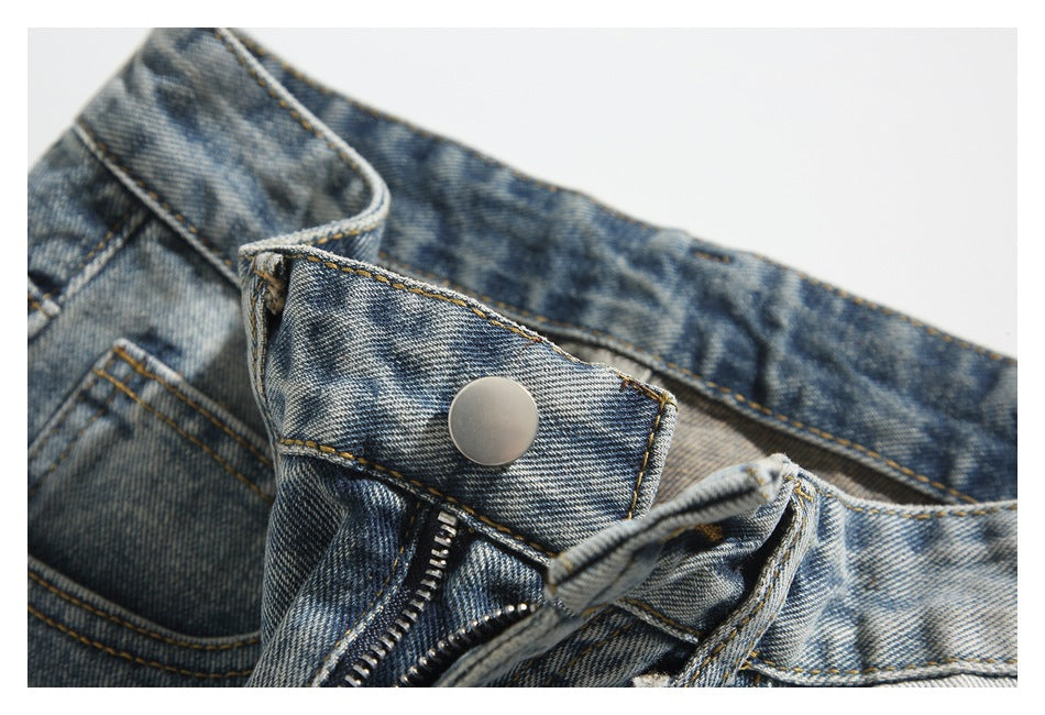 Close-up of the metal button and partially open zipper fly on washed blue jeans.