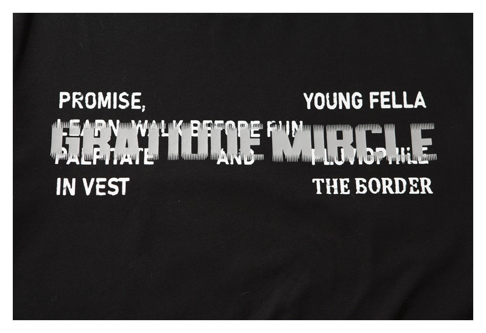 Close-up of a black T-shirt with white English lettering and a large distorted block-letter graphic across the chest.