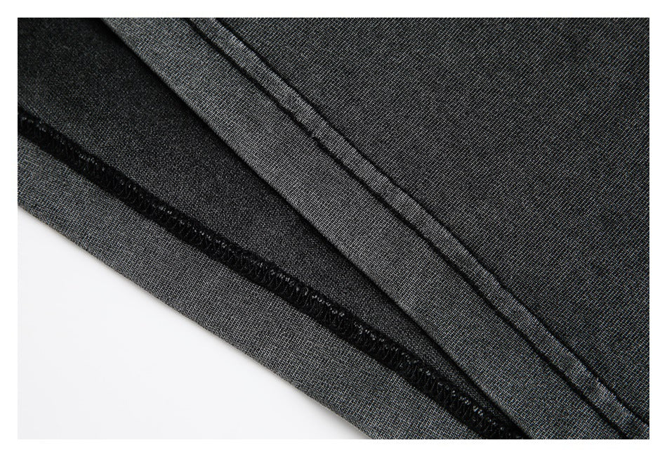 Close-up of a charcoal sweatshirt hem with visible overlock stitching and folded fabric.