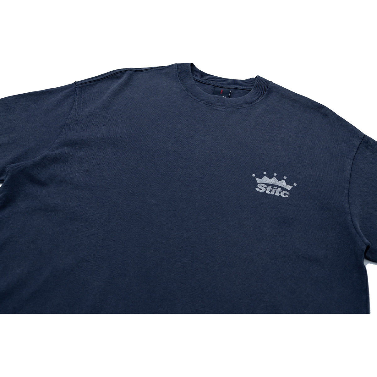 Close-up of a dark navy crew-neck T-shirt with a small silver crown and wordmark on the chest.