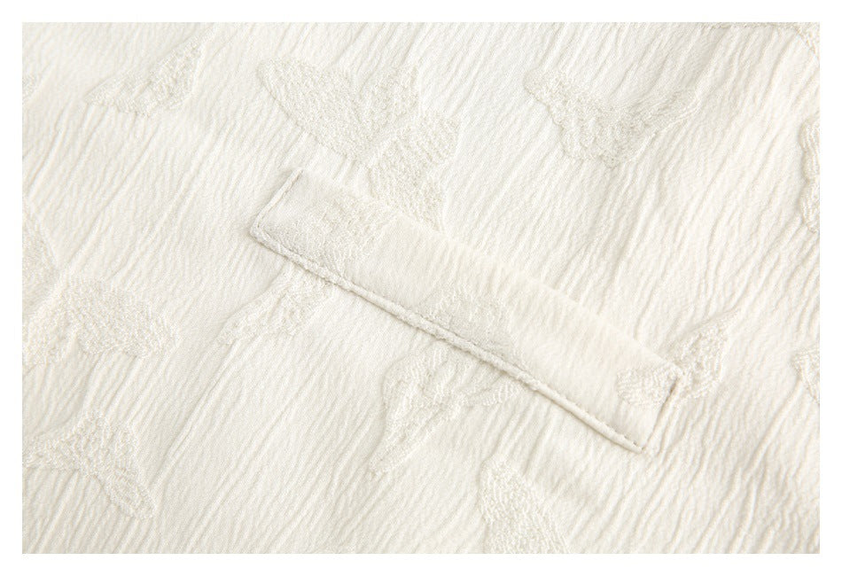 Close-up of a small pocket flap on ivory fabric with raised woven motifs.