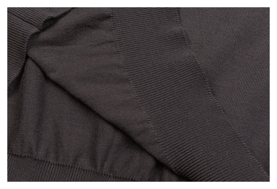 Close-up of a charcoal knit garment showing a ribbed band and nearby seam construction.