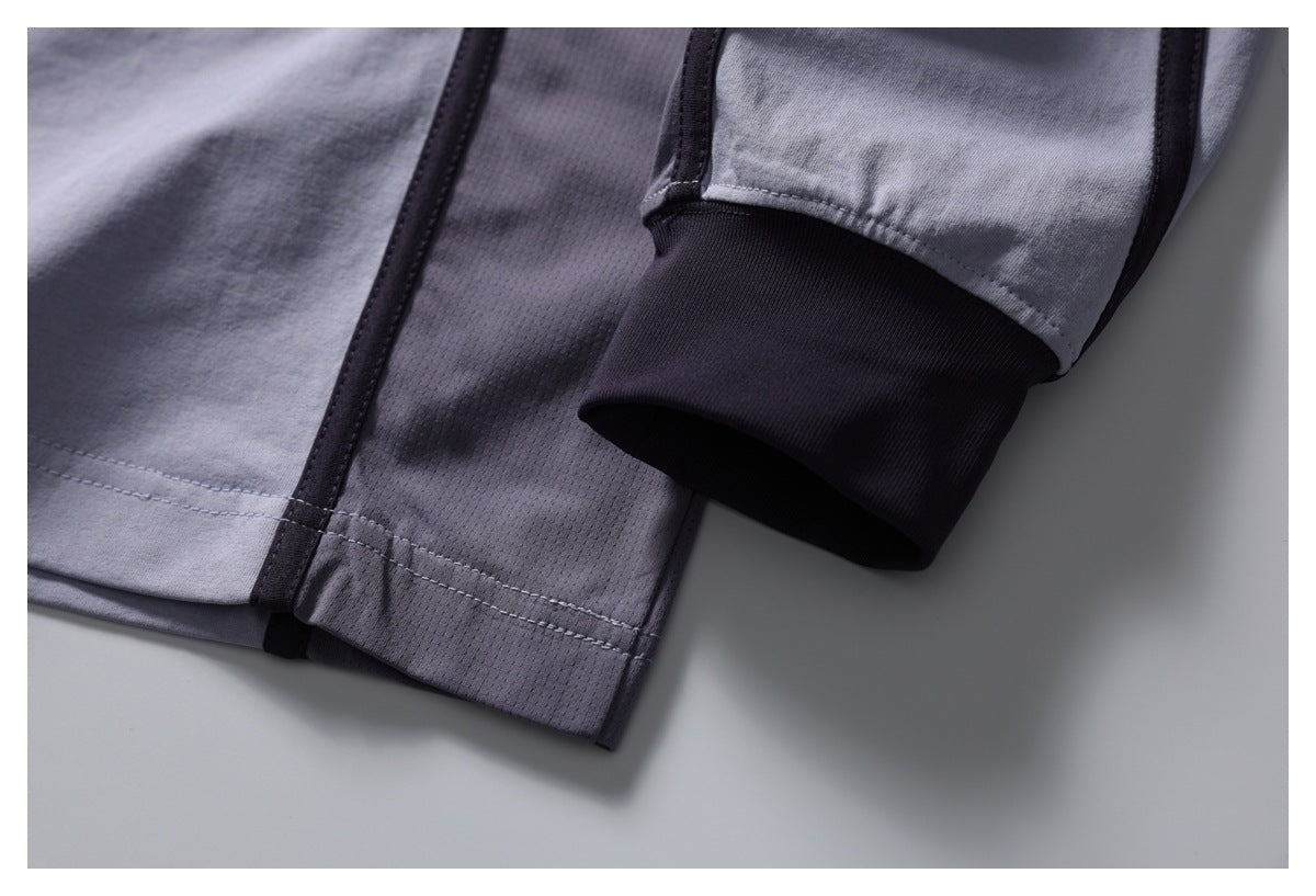 Close-up of the light gray shirt's dark ribbed cuff, side panel, and stitched hem.