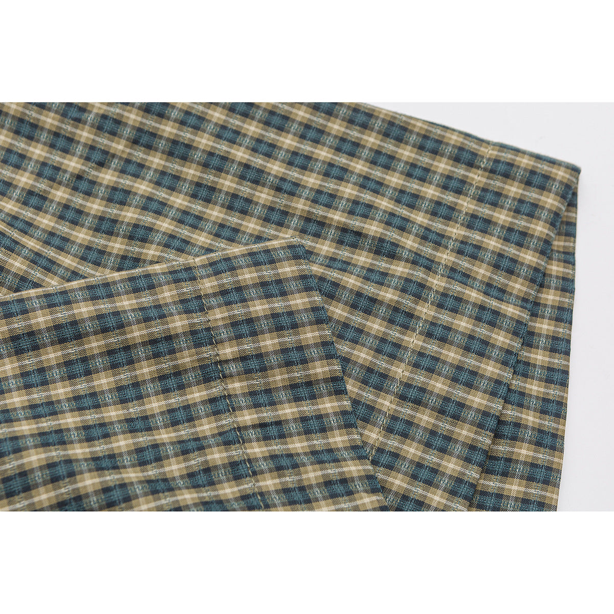 Close-up of overlapping teal, brown, and cream plaid shirt fabric.