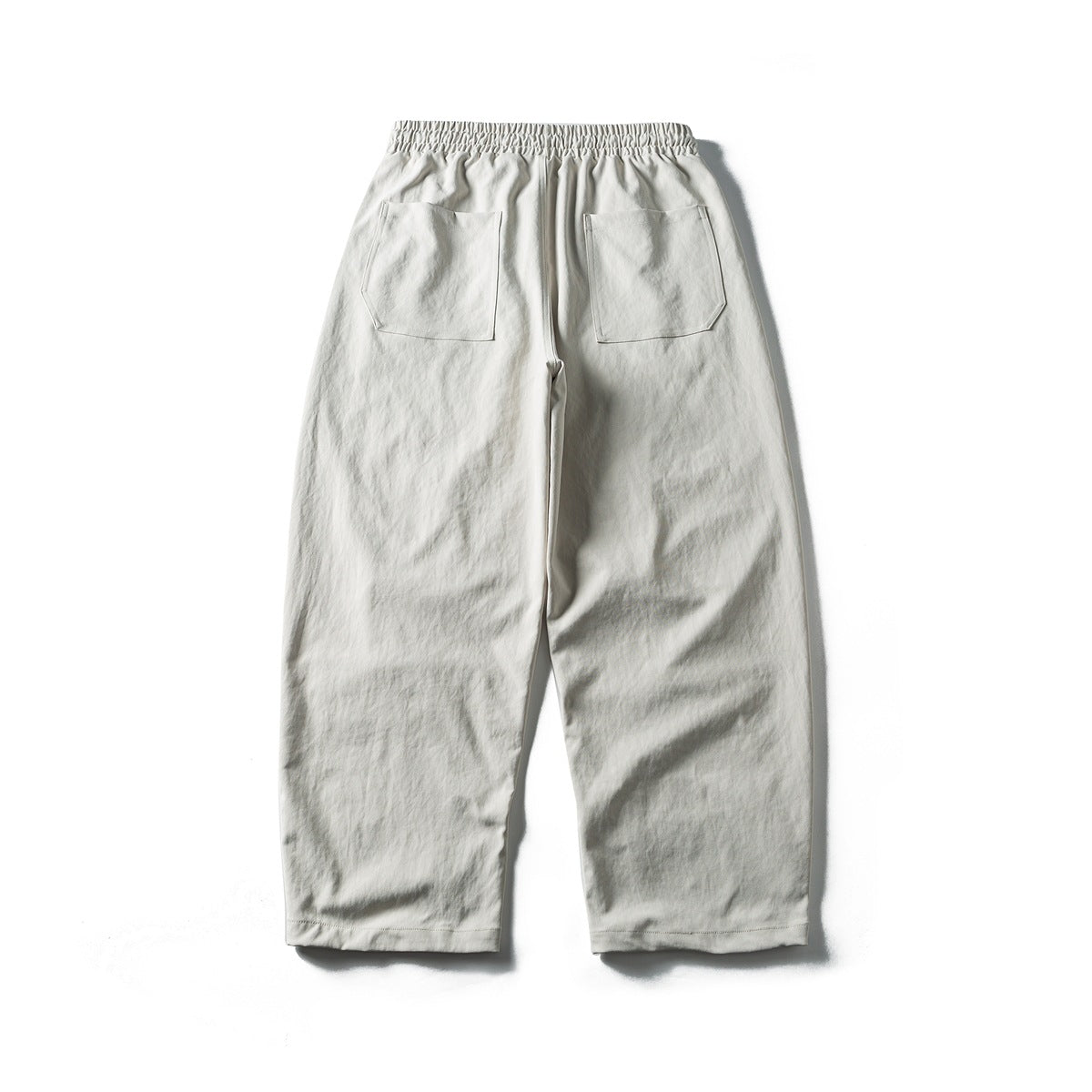 Back view of light gray loose trousers with an elastic waistband and two patch pockets.