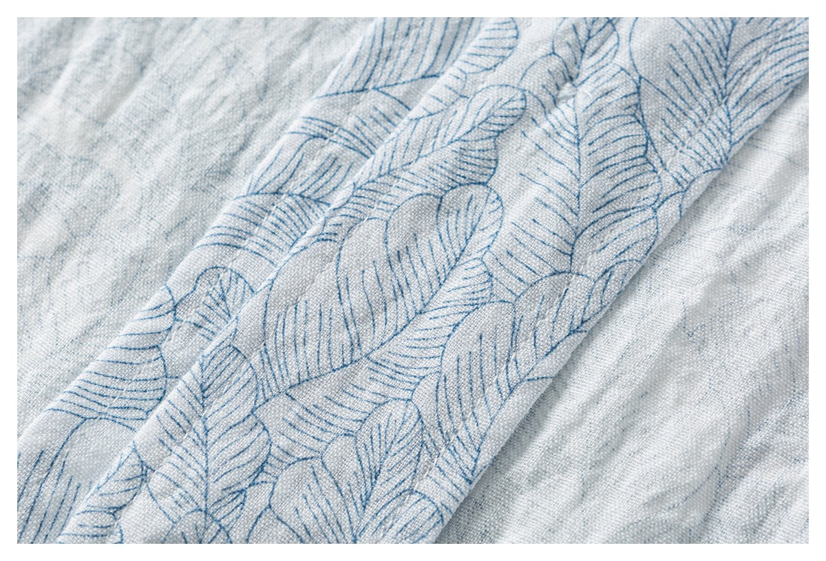 Close-up of pale blue-gray fabric with a repeating blue leaf pattern and visible woven texture.