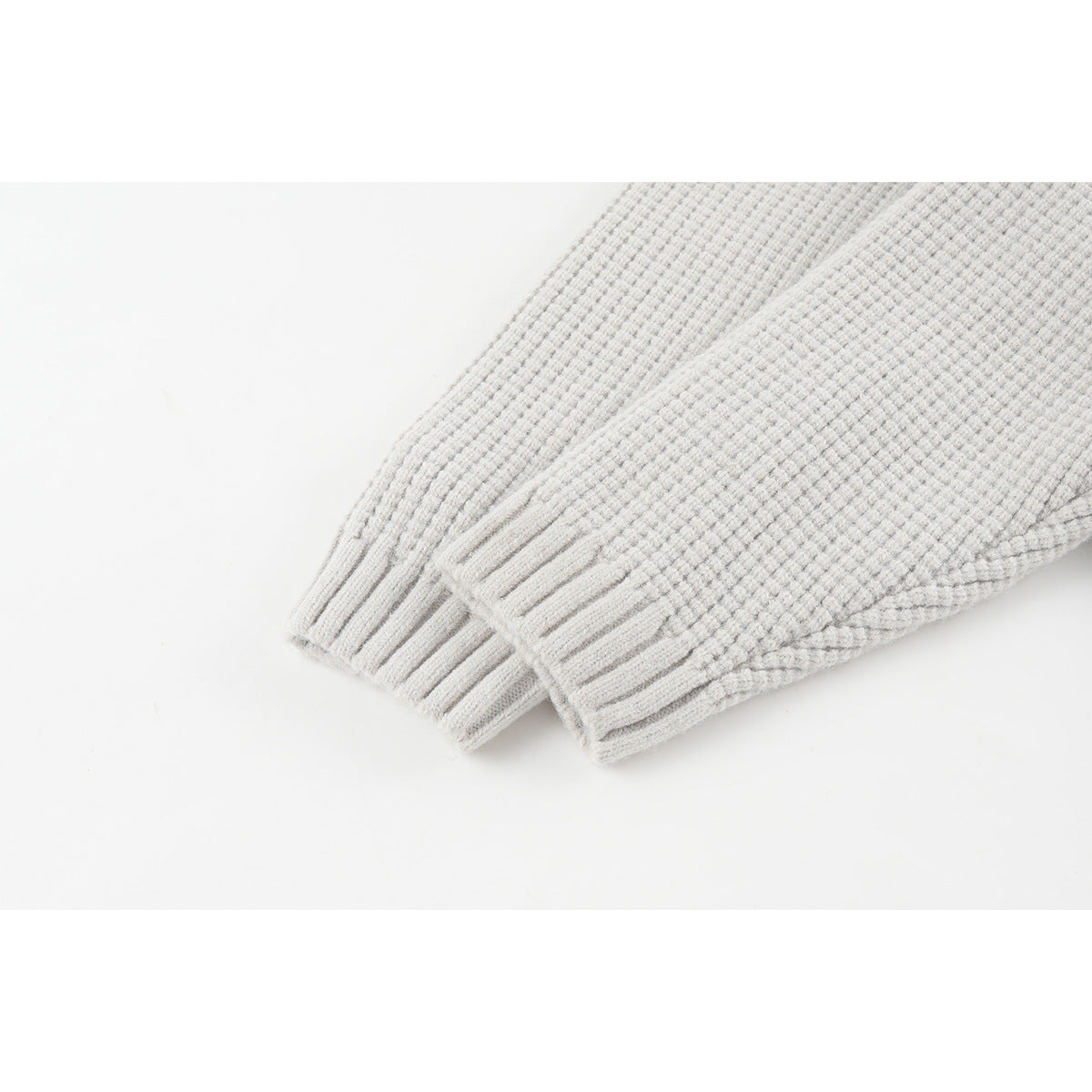 Close-up of a light gray textured knit cardigan's ribbed sleeve cuffs.