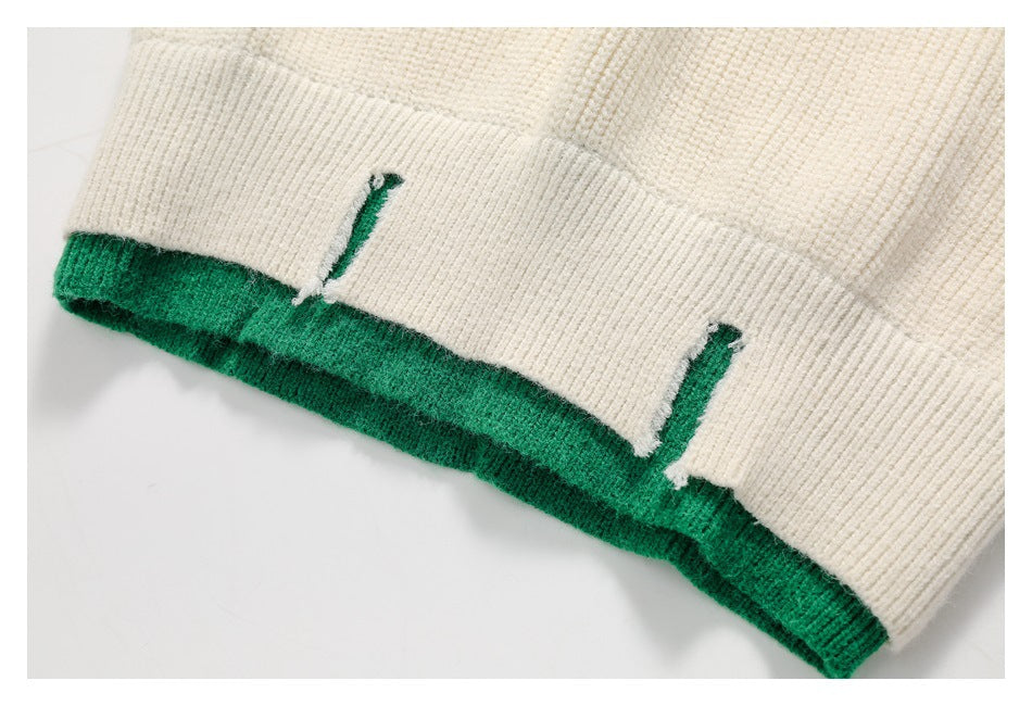 Close-up of ivory rib-knit fabric with emerald green edging and two narrow openings.