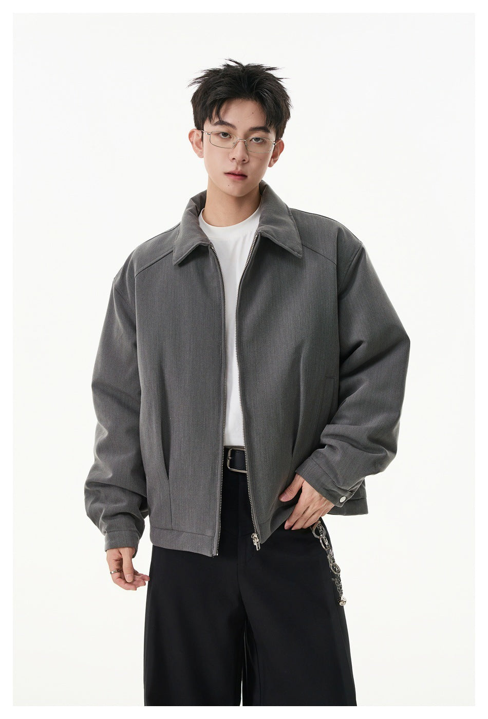 Model wearing a charcoal gray zip-front jacket with a pointed collar and roomy sleeves over a white shirt.