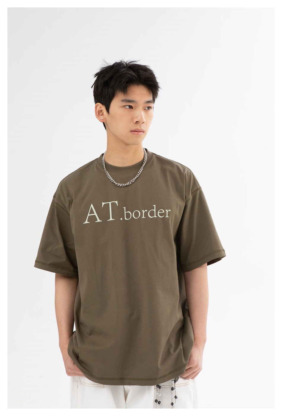 Front view of a model wearing an olive-brown oversized T-shirt with pale lettering.