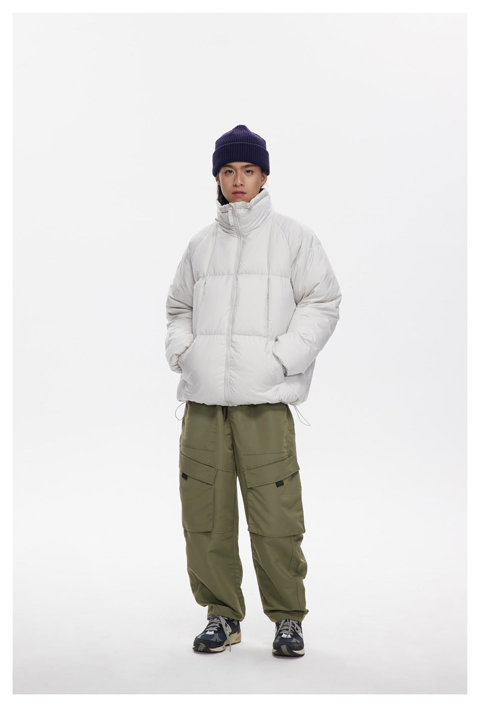 Full-length model wearing a zipped white puffer jacket with a high collar and olive cargo pants.