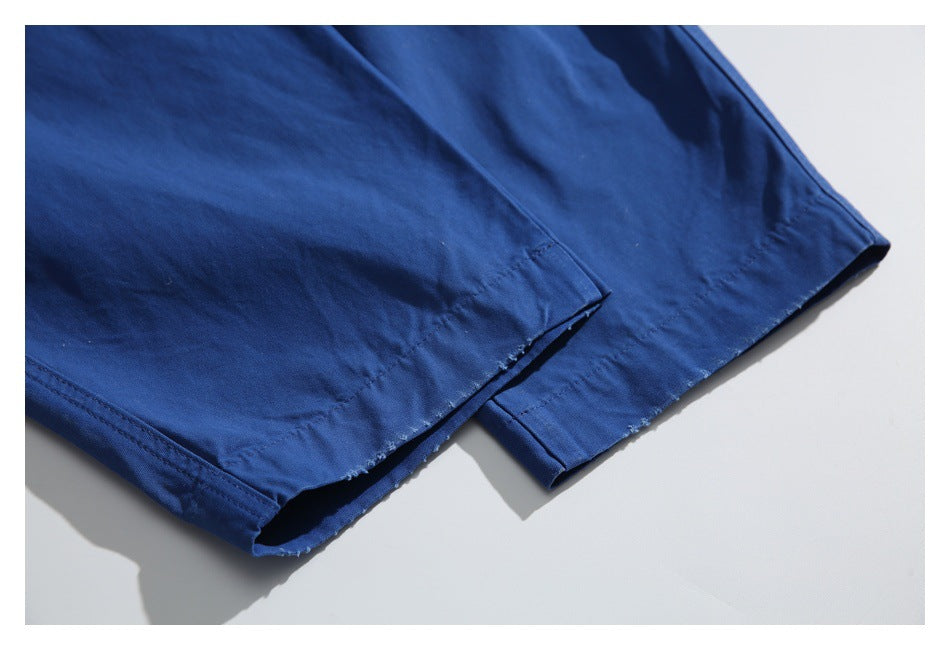 Close-up of the hems of royal-blue trousers laid flat, showing stitched edges and overlapping legs.