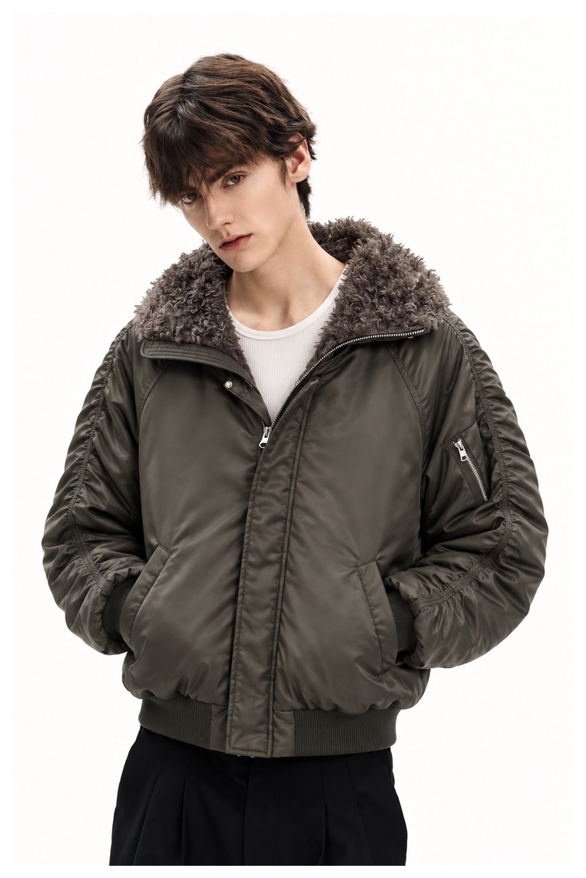 Upper-body view of a male model wearing a dark olive bomber jacket with a plush gray collar and sleeve zipper pocket.