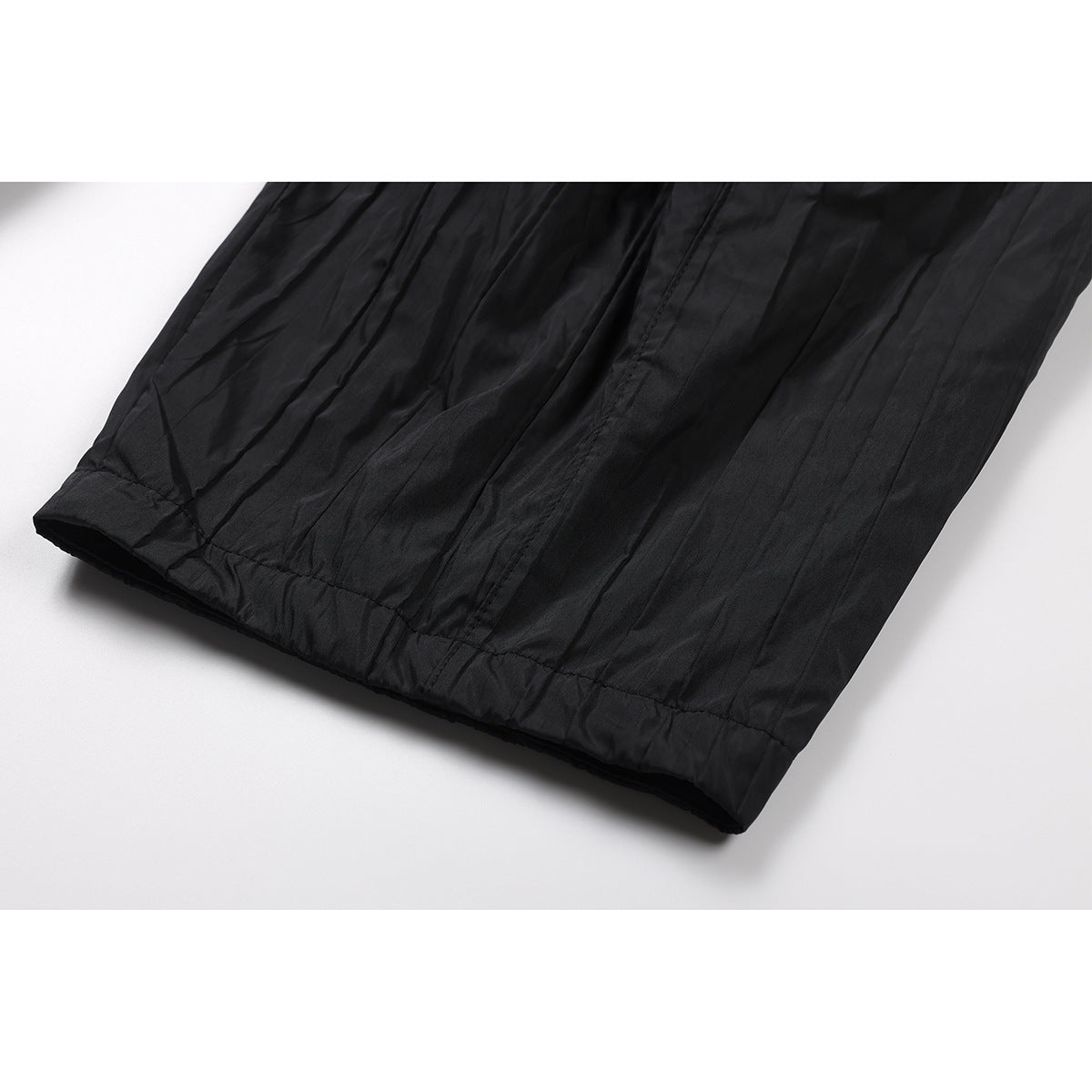 Close-up of the straight hem and creased fabric on black trouser legs.
