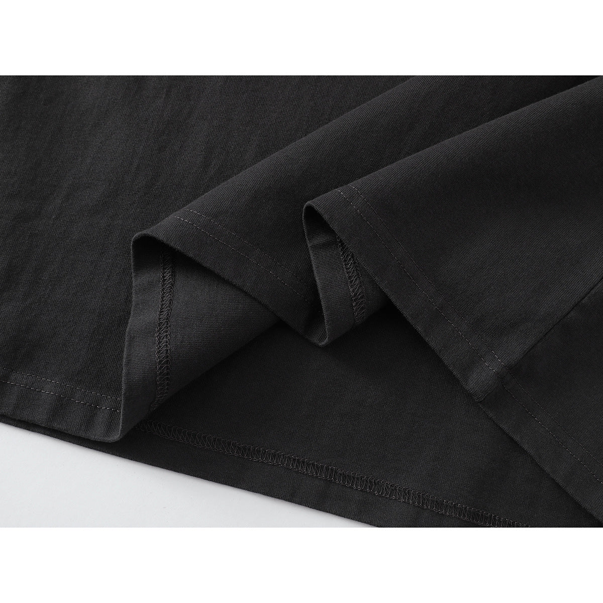 Close-up of a charcoal shirt's folded hem, double stitching, and overlocked interior seams.