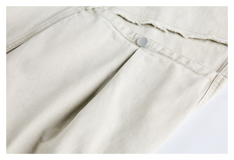 Close-up of light beige trousers showing a metal button and frayed seam.