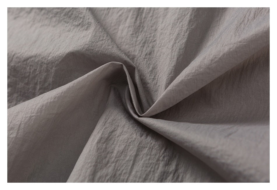 Close-up of gray fabric gathered into soft folds, showing its crinkled surface.