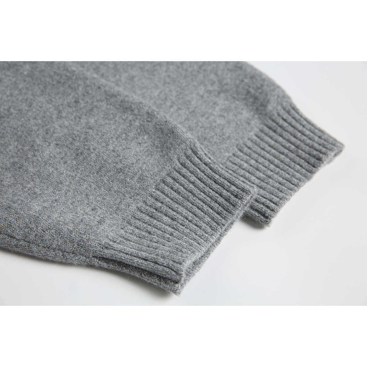 Close-up of a gray knit sweater sleeve with a wide ribbed cuff.