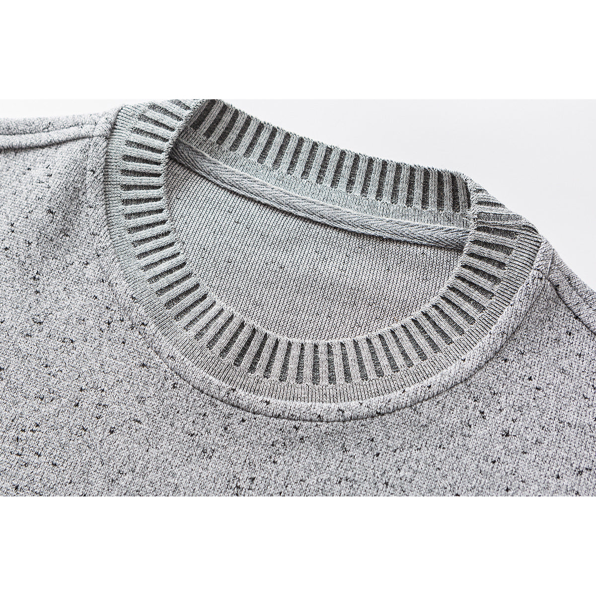 Close-up of a speckled light gray top with a round neckline and dark striped ribbed trim.