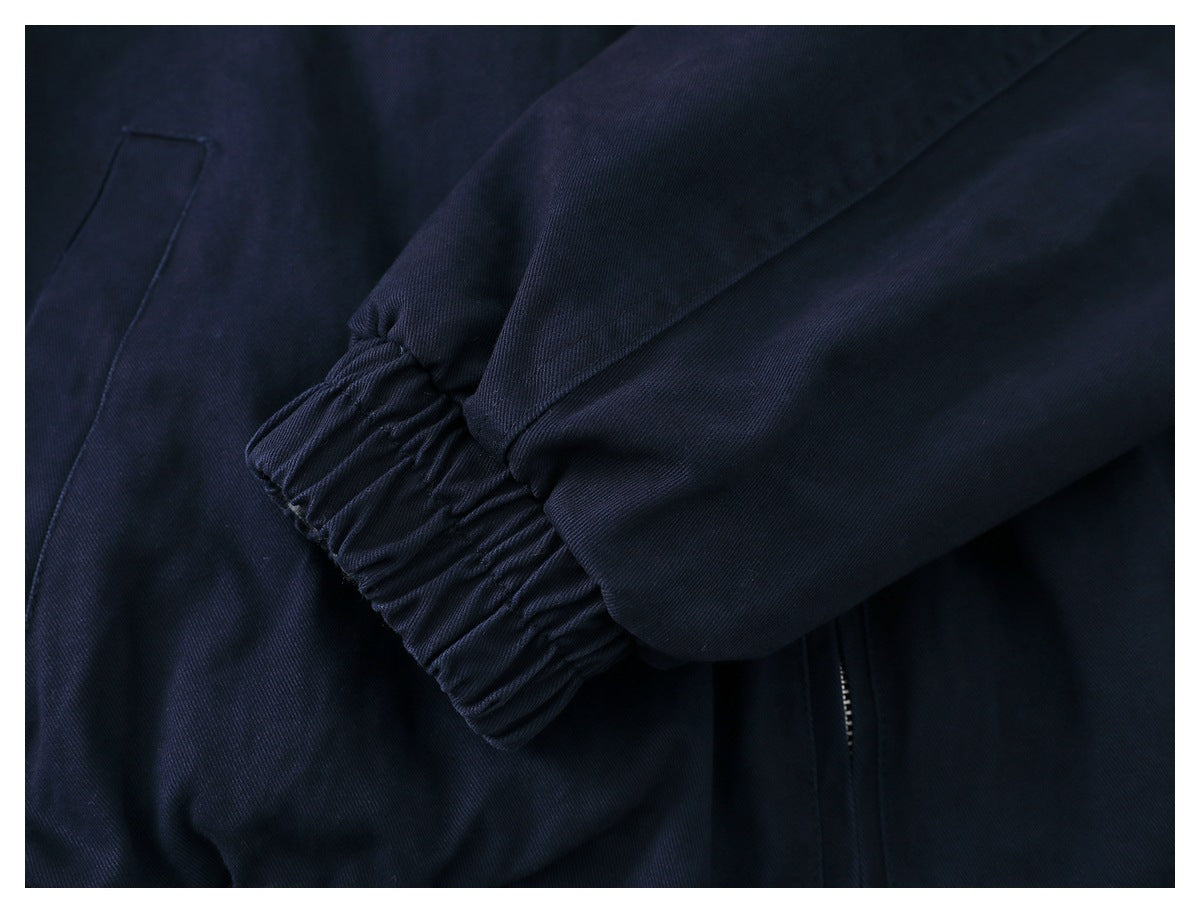 Close-up of a dark navy garment sleeve with a gathered elastic cuff, stitching, and a partial zipper.
