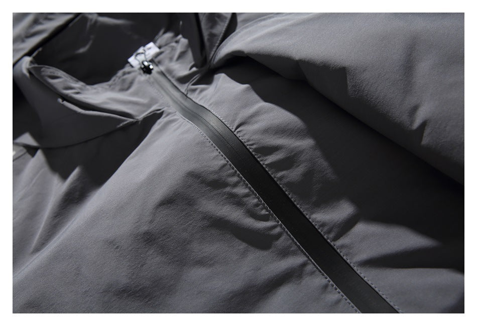 Close-up of a charcoal gray jacket showing the front zipper and stitched panels.