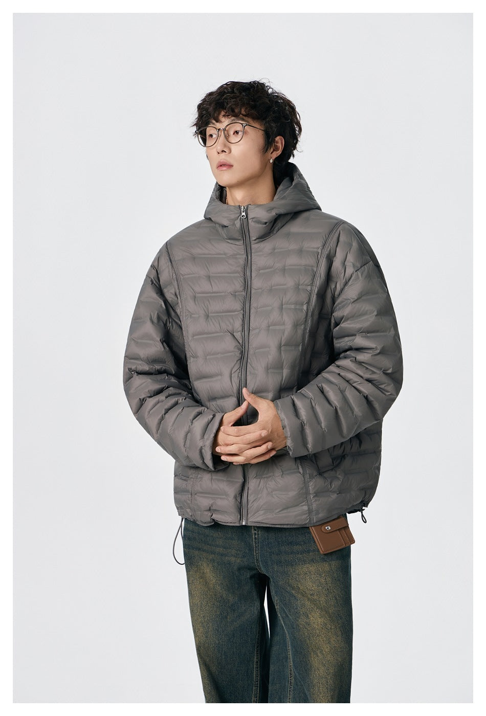 Model wearing a gray quilted hooded jacket zipped up, shown from the waist up.