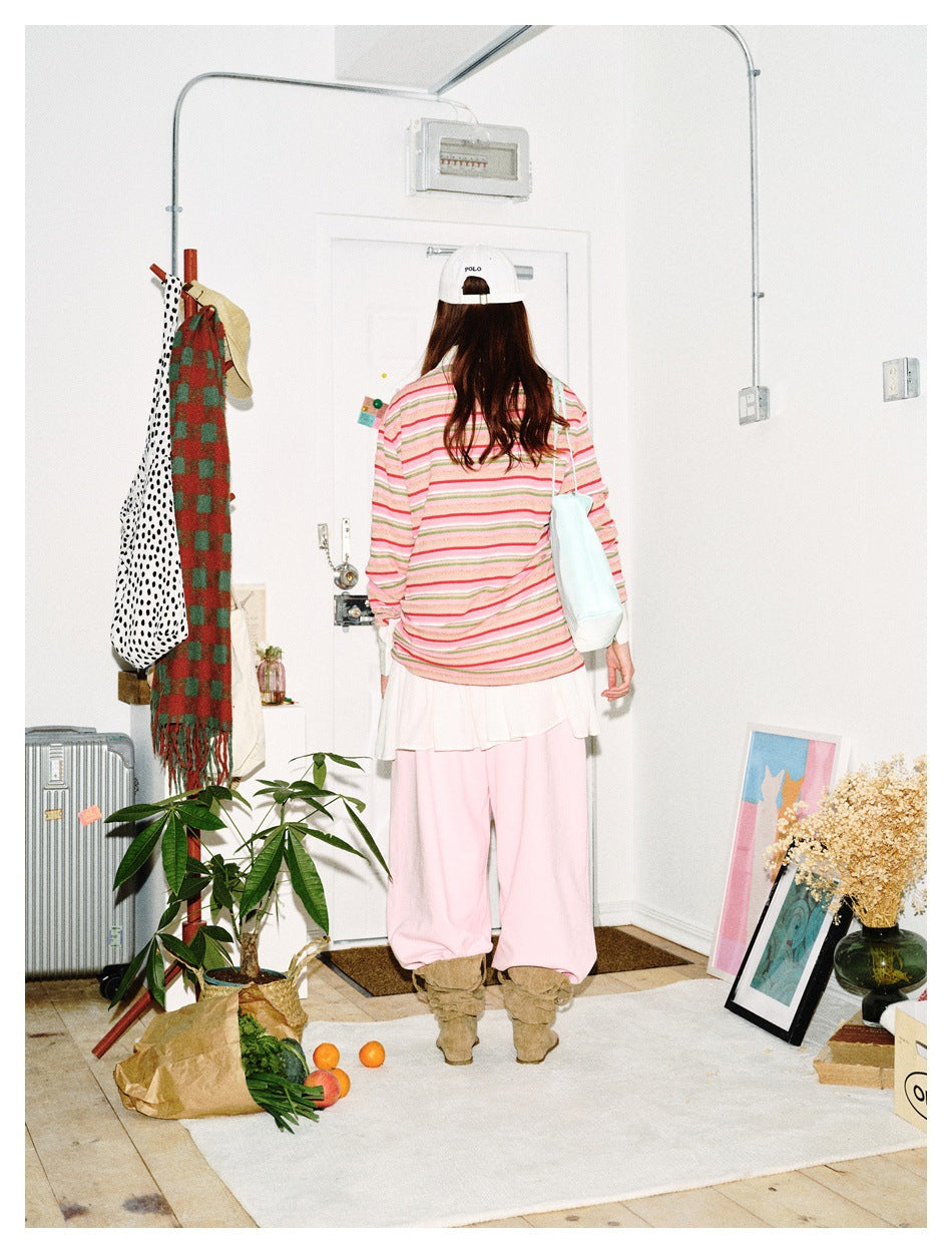 Back view of model wearing a pink, green and white striped long-sleeve top, white skirt and pink trousers.