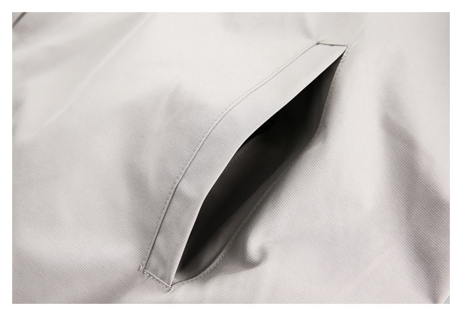 Close-up of a slanted welt pocket on light gray apparel.