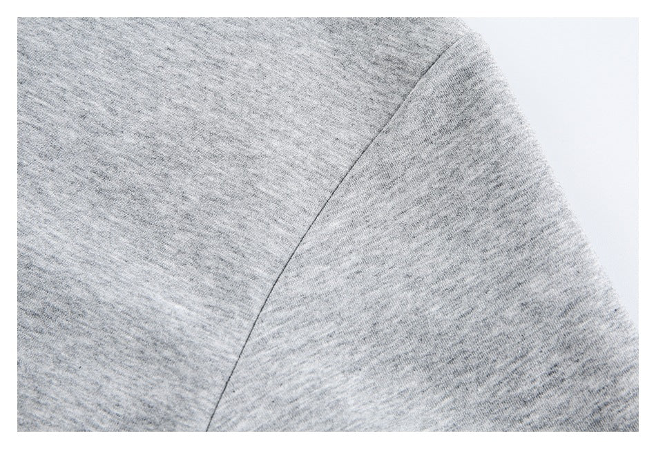 Close-up of a shoulder seam on a light gray heathered garment.