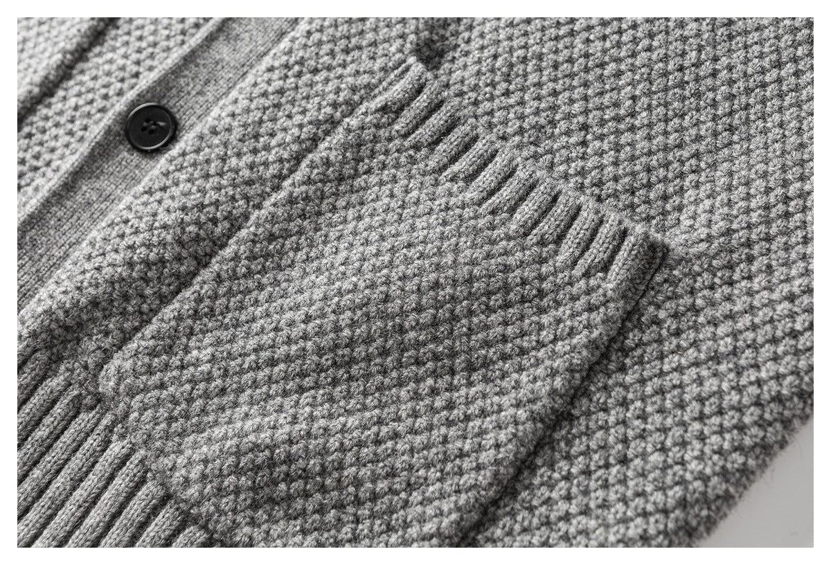 Close-up of a gray textured knit cardigan pocket beside the button placket.