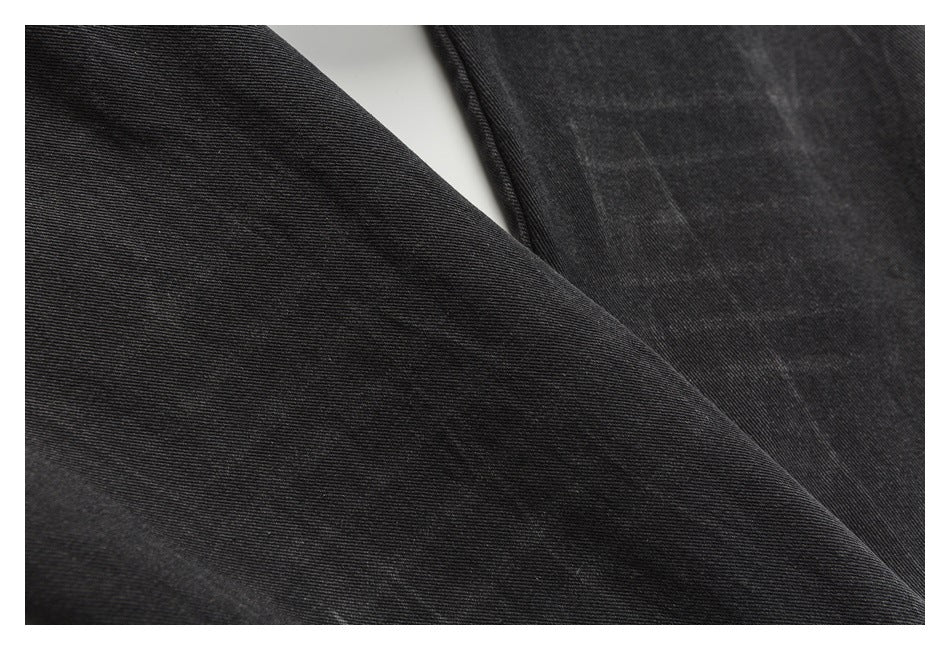 Close-up of black denim fabric showing its diagonal twill texture and a stitched seam.