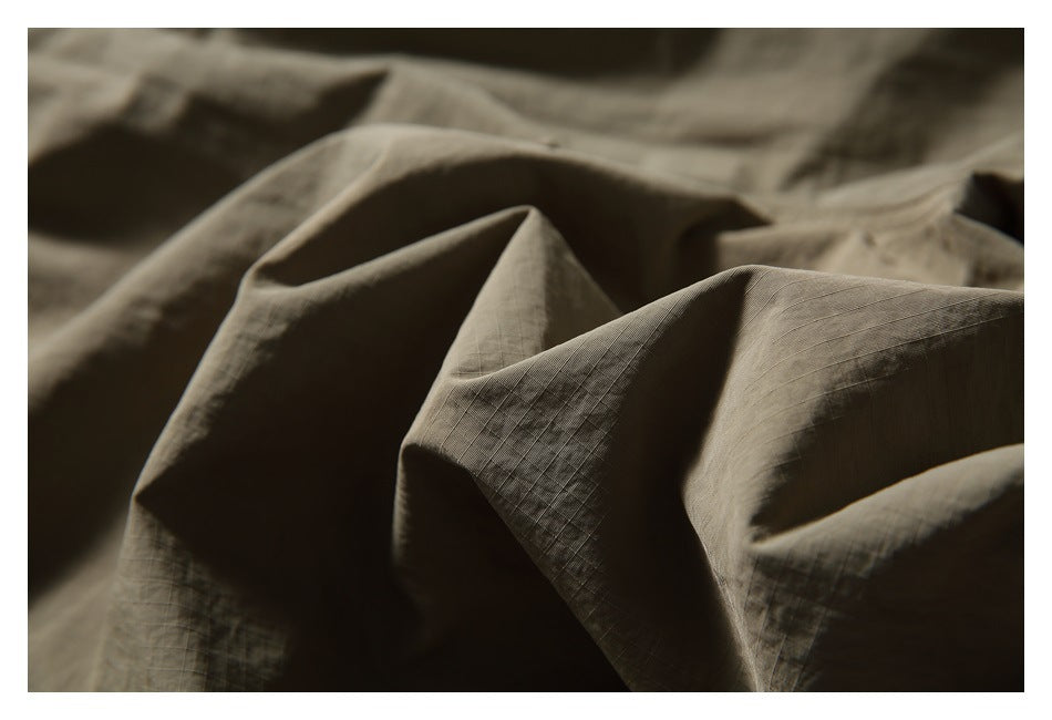 Close-up of olive-khaki fabric folded to show its fine grid-like texture.