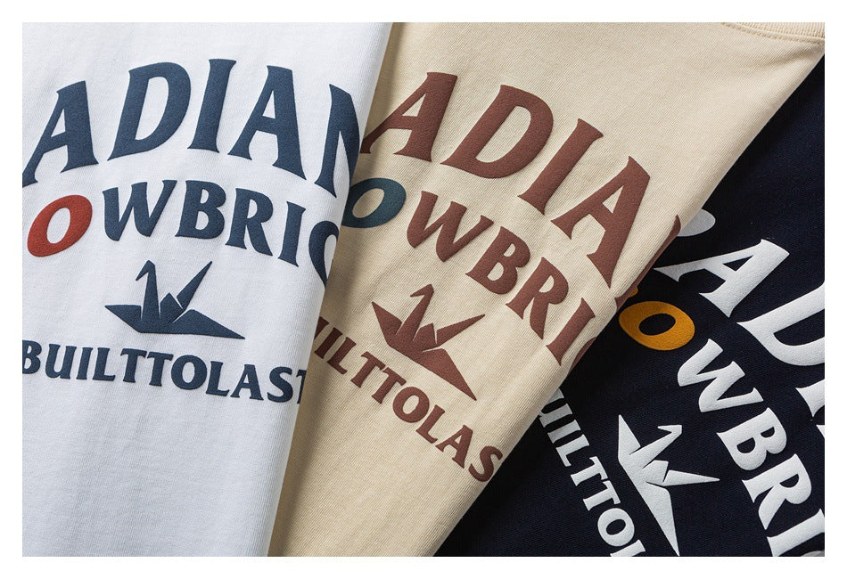 Close-up of white, beige, and navy T-shirts showing variations of the same colorful chest graphic.