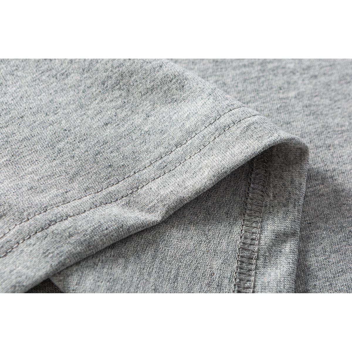 Close-up of heather gray T-shirt fabric showing a folded edge, double stitching, and an overlocked seam.